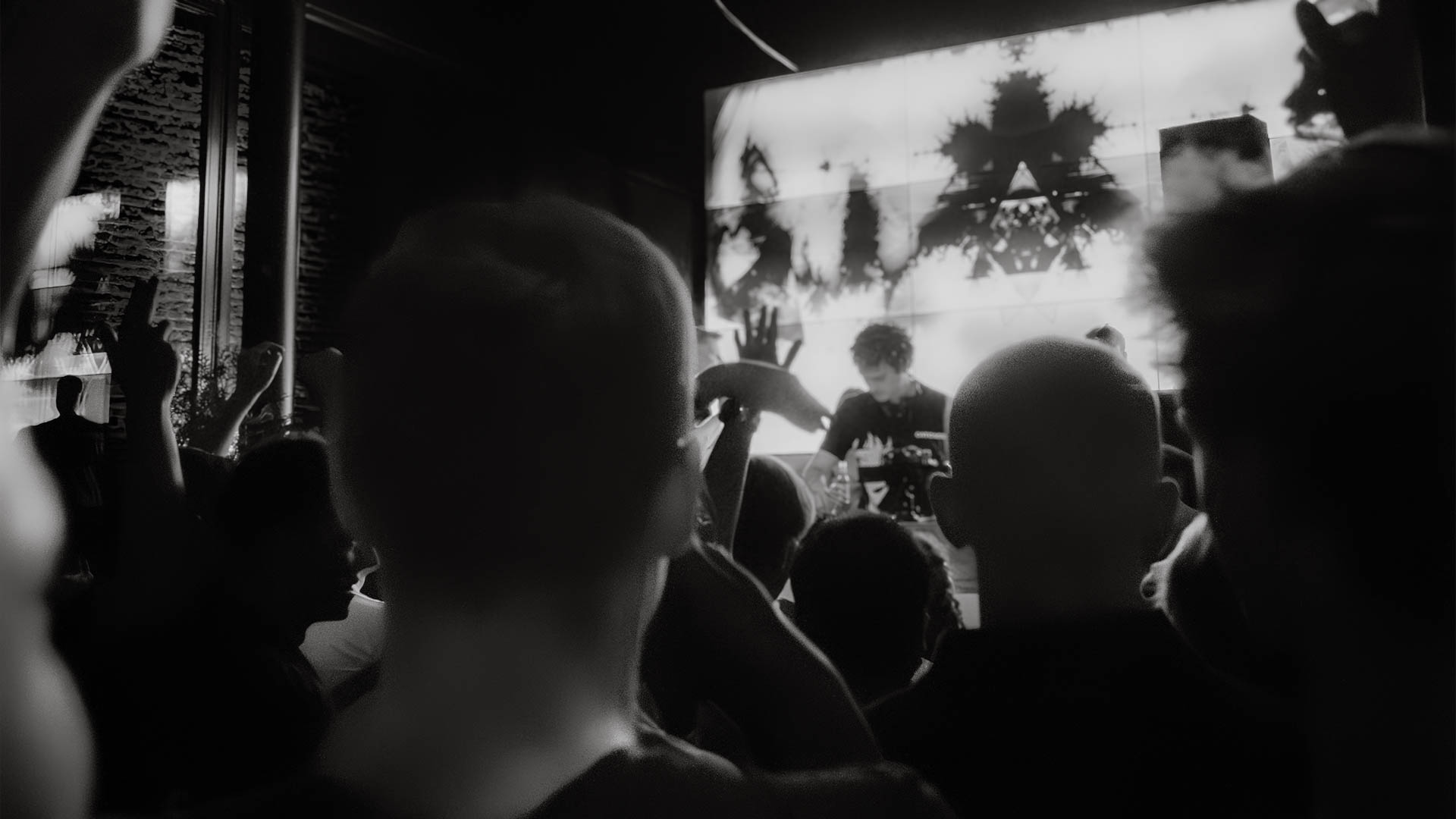 Silhouette of a DJ in front of a bright screen